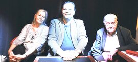 3 Personen sitzen an einem Tisch