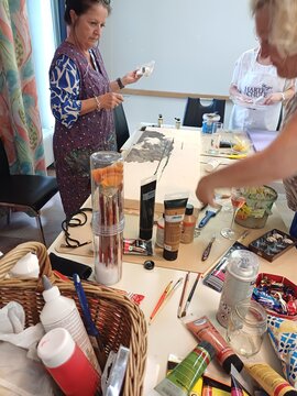 Tisch mit Malfarben, Pinseln und einer Frau