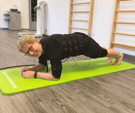 Ältere Dame auf Matte am Boden im Training 